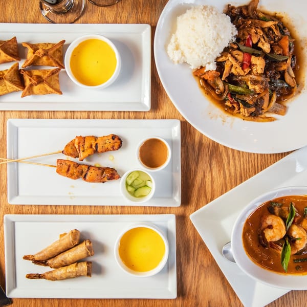 Overhead view of various Thai dishes including curry, satay, spring rolls, and crab rangoons.