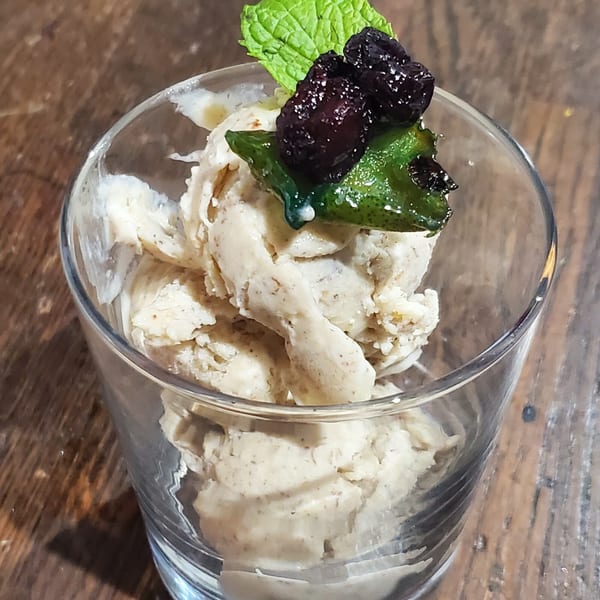Scoops of Baan Thai ice cream in a glass, topped with mint and dark berries.