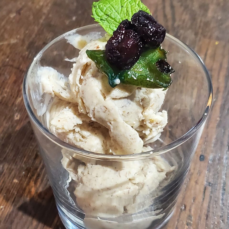 Scoops of Baan Thai ice cream in a glass, topped with mint and dark berries.
