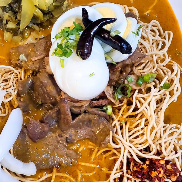 Close-up of Baan Thai's Khao Soi with beef, egg, crispy noodles, and pickled greens.